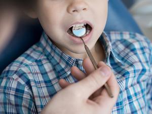 Ein Zahnarzt untersucht das Gebiss eines kleinen Jungen. (Symbolfoto)