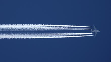  Ein Flugzeug der Qatar Airline hinterlässt am wolkenlosen Himmel Kondensstreifen.
