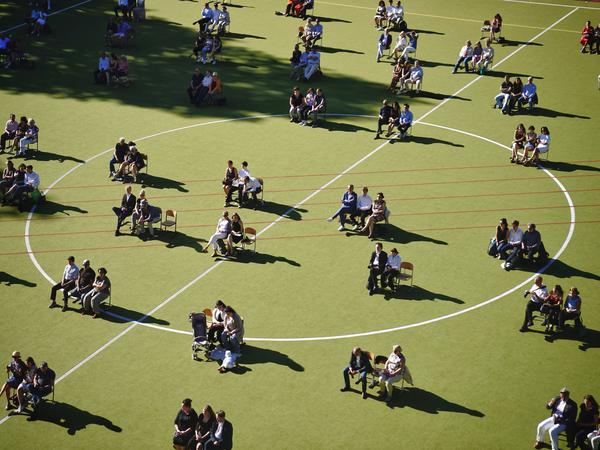 Auf dem Sportplatz des Rheingau-Gymnasiums versammeln sich im Juni die diesjährigen Abiturienten mit ihren Angehörigen für die Vergabe ihrer Zeugnisse. Dafür werden hier die geltenden Corona-Abstandsregeln eingehalten.