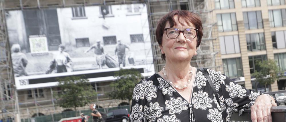 Elke Rosin auf dem Gendarmenmarkt vor einem Grossplakat mit dem Bild ihrer Flucht.