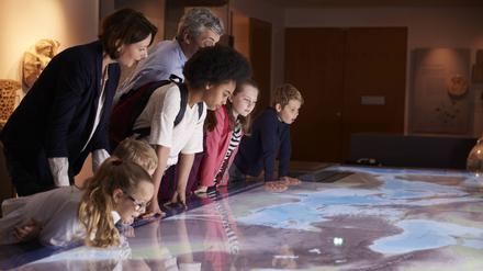 Kinder und Erwachsene schauen sich eine Landkarte im Museum an.