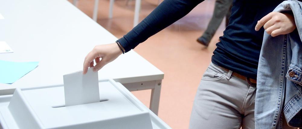 Eine junge Wählerin wirft einen Stimmzettel in die Wahlurne.