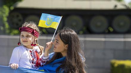 Friedlich. Eine Frau mit einem Kind auf dem Arm halten bei einer Veranstaltung vor dem Sowjetischen Ehrenmal im Tiergarten eine große ukrainische Fahne.