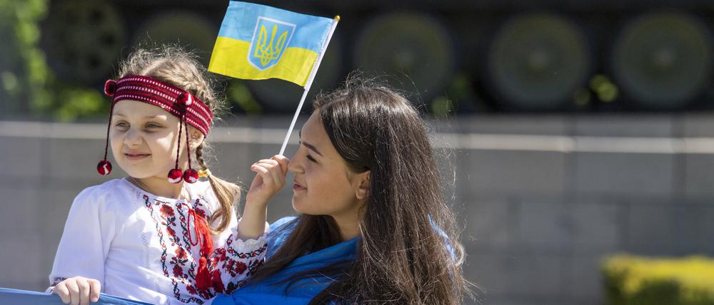 Friedlich. Eine Frau mit einem Kind auf dem Arm halten bei einer Veranstaltung vor dem Sowjetischen Ehrenmal im Tiergarten eine große ukrainische Fahne.