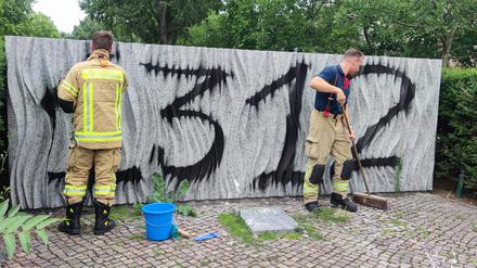 Feuerwehr-Männer versuchen, das Ehrenmal am Mariannenplatz zu reinigen
