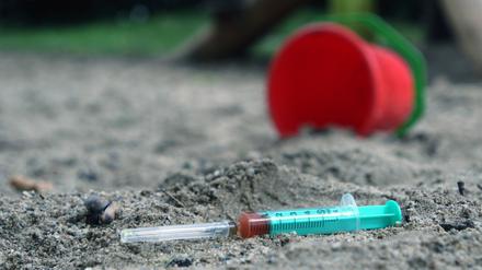 Die Einwegspritze einer drogenabhängigen Person liegt zurückgelassen auf einem Kinderspielplatz (Symbolbild).