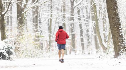 Ein Mann läuft im Dezember 2021 durch den verschneiten Tiergarten.