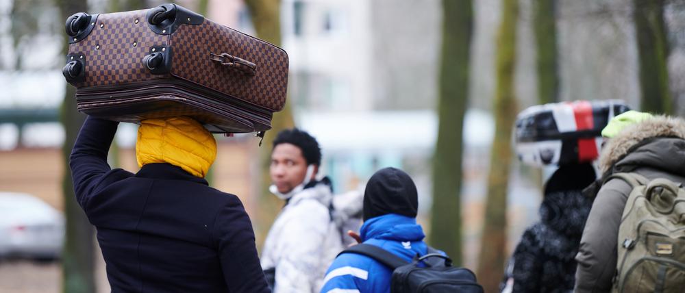 Kriegsflüchtlinge aus der Ukraine tragen ihre Koffer auf dem Kopf, während sie ins Ankunftszentrum Reinickendorf gehen.