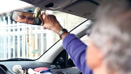 Eine Teilnehmerin eines Fahrtrainings für Senioren ab 65 Jahren ihren Rückspiegel ein. 