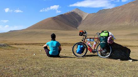 Anne Westwards sitzt in der Landschaft am Ala Bel Pass in Kirgisistan.