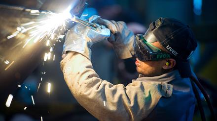 Ein Mann aus Somalia, der zuvor in Deutschland als Schweißer ausgebildet wurde, arbeitet in einer Firma an einem Stahlsegment.