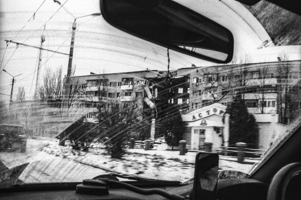 Blick aus dem Auto auf ein zerstörtes Gebäude.