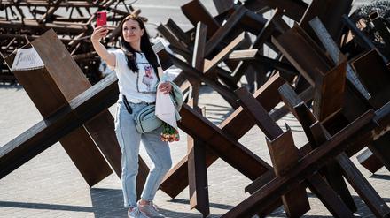 Eine Frau macht in Kiew ein Selfie an einer Panzersperre.