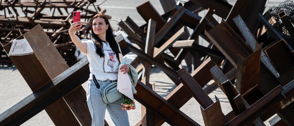 Eine Frau macht in Kiew ein Selfie an einer Panzersperre.