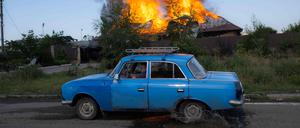 Ein Ukrainer fährt am 27. Juni 2022 an einem brennenden Haus in der Nähe von Bachmut vorbei.