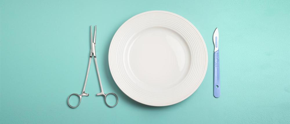 Close up of a pair of pincers  and scalpel by a plate, post operative food in hospital.  What can I eat after an operation?