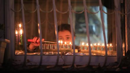Lichterfest im Schatten des Krieges. Ein Mädchen zündet in Jerusalem eine Kerze auf der traditionellen Chanukkia an.