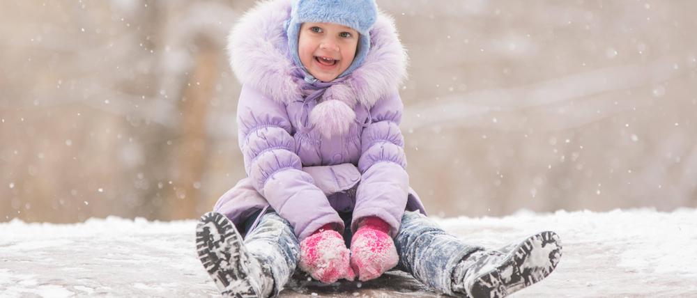 Joyful child slides down the icy hill