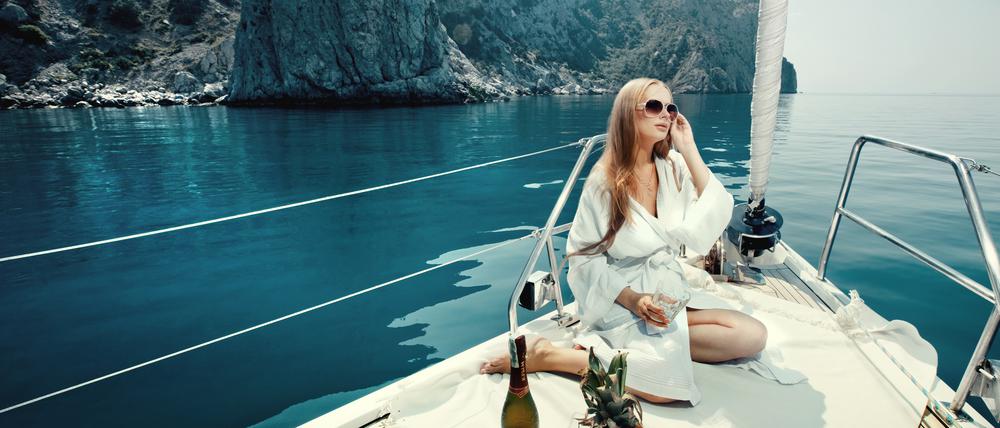 Luxusurlaub auf einer Yacht, mit Weinflasche und exotischen Früchten.