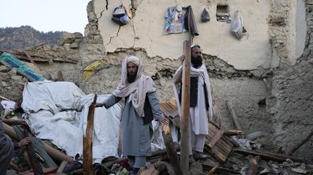 23.06.2022, Afghanistan, Gayan: Zwei Afghanen stehen in den Trümmern eines Hauses. Nach dem verheerenden Erdbeben in der afghanisch-pakistanischen Grenzregion hat Regen die Rettungsarbeiten erschwert. Foto: Ebrahim Noroozi/AP/dpa +++ dpa-Bildfunk +++