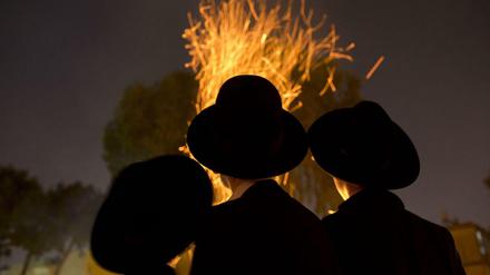 Orthodoxe Juden versammeln sich in Israel an einem Lagerfeuer während eines jüdischen Festes.