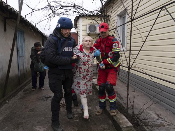 Evgeniy Maloletka hilft einem Sanitäter bei der Versorgung einer durch Beschuss verletzten Frau.
