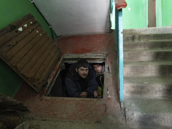 Menschen verstecken sich hinter einer Kellerluke vor den Angriffen der russischen Armee.