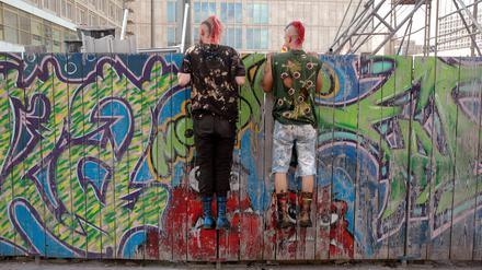 Zaungäste der modernen Stadtplanung: Zwei Punker schauen sich eine Berliner Baustelle an.