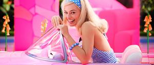 Margot Robbie sitzt als Barbie in einem pinken Cabrio.