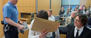 Der Angeklagte Sanel M. wird am 24.04.2015 zu Verhandlungsbeginn in einen Sicherheitssaal des Landgerichts in Darmstadt geführt und nimmt neben seinem Anwalt Stephan Kuhn (r) Platz.
