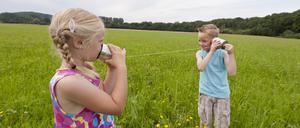 Germany, North Rhine-Westphalia, Hennef, Boy and girl in meadow playing with tin can phone model released PUBLICATIONxINxGERxSUIxAUTxHUNxONLY KJF000135