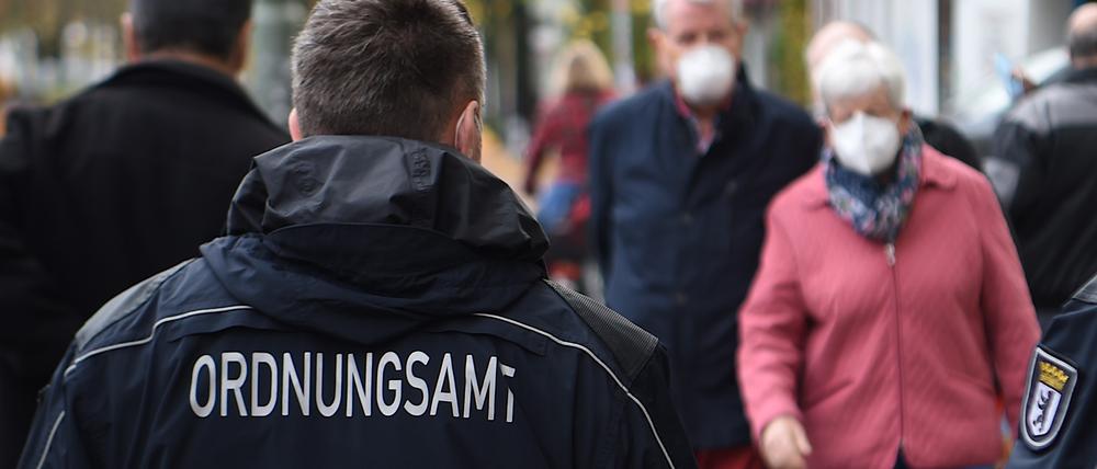 Mitarbeiter vom Ordnungsamt kontrollieren, ob die Passanten auf der Bergmannstraße die Maskenpflicht einhalten.