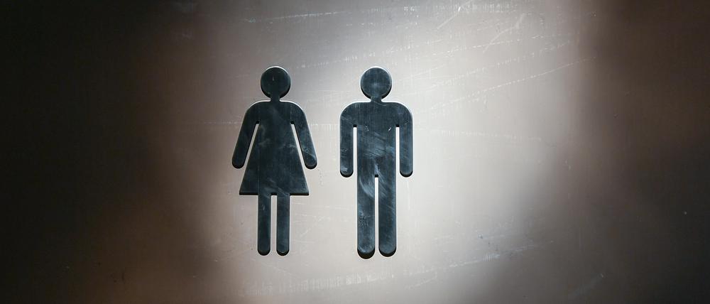 Piktogramme für eine Frau und ein Mann sind an einer Toiletten-Tür angebracht.