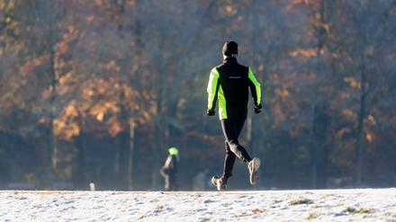 Ein Mann joggt durch den winterlichen Stadtpark.
