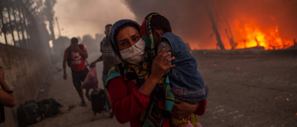 Eine Frau schützt ihr Kind vor den Flammen in Moria.