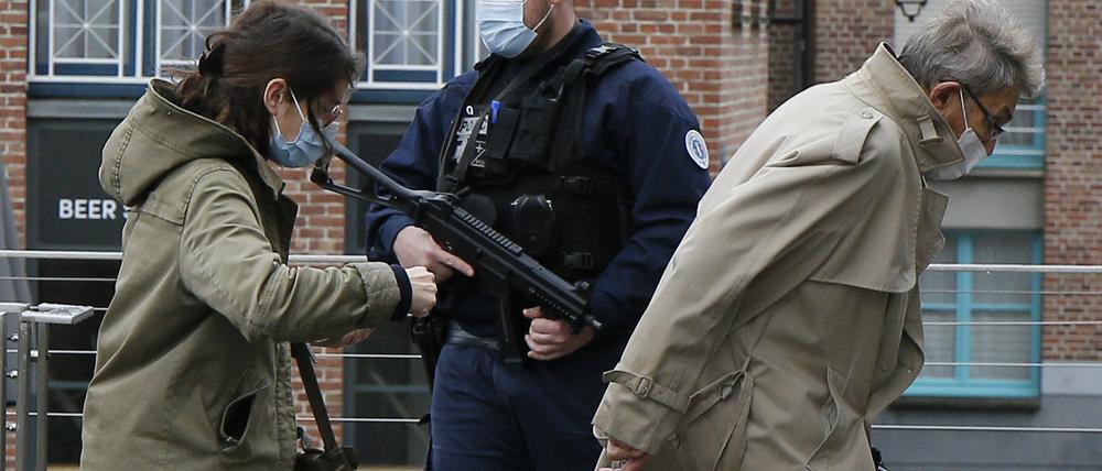 Passanten gehen an einem französischen Polizisten vorbei, der vor der Kirche Notre-Dame Wache steht. 