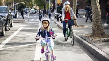 Portrait of mother and daughter riding bicycles on street