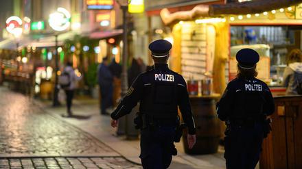 Polizisten gehen am Abend in der Dresdner Altstadt an Restaurants entlang.