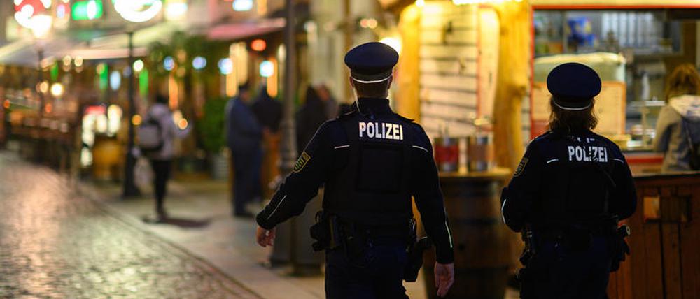 Polizisten gehen am Abend in der Dresdner Altstadt an Restaurants entlang.