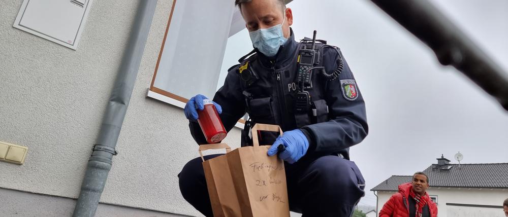 Polizisten sichern Beweismittel, nachdem Unbekannte Grabkerzen mit der Aufschrift „Impfopfer“ vor Praxen, einem Wohnhaus und dem Siegener Rathaus platziert hatten. 