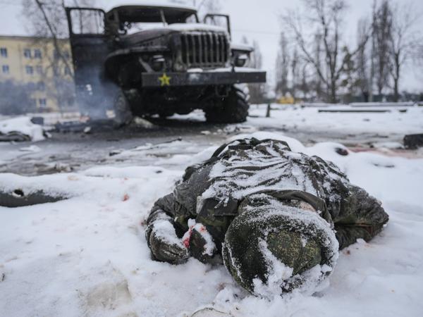 Die Leiche eines Soldaten liegt schneebedeckt neben einem zerstörten russischen Militärfahrzeug.