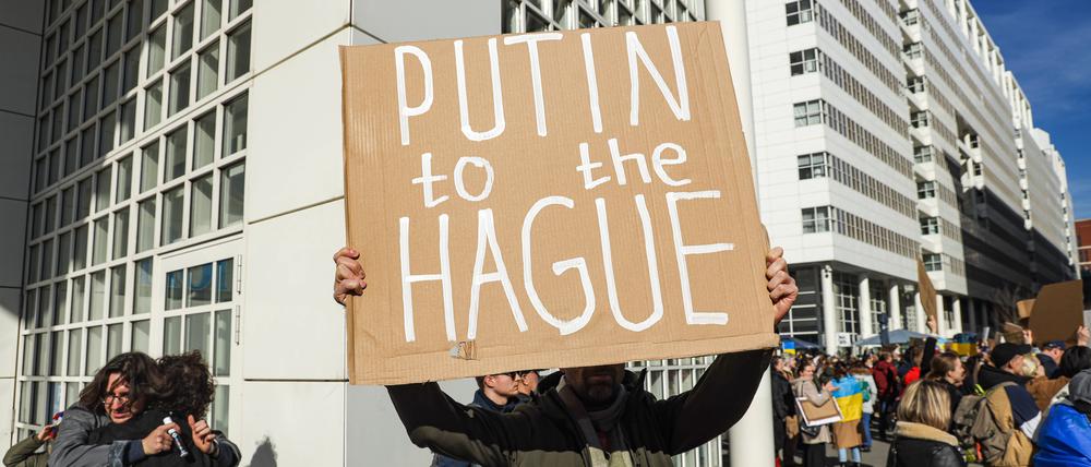 Ein Demonstrant fordert die Überstellung des russischen Präsidenten Wladimir Putins nach Den Haag (englisch: „The Hague“), wo der Internationale Strafgerichtshof sitzt.