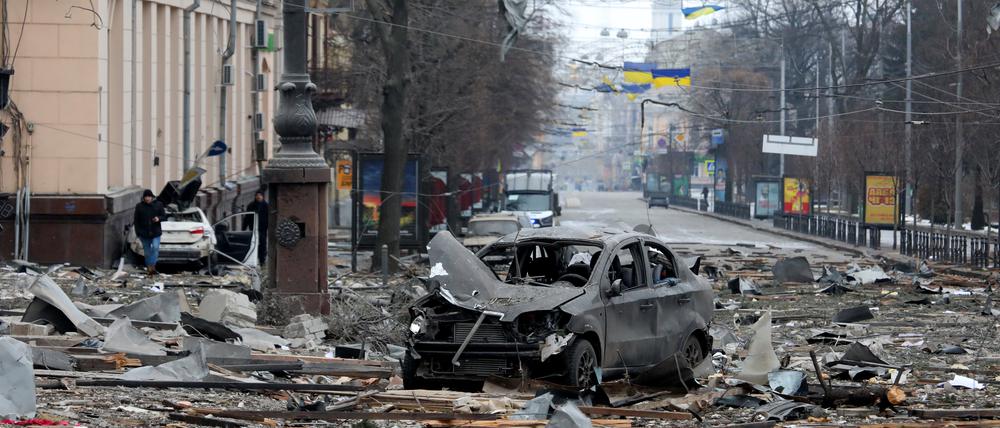 Ein ausgebranntes Autos steht auf der Straße in der Nähe des durch Angriffe zerstörten Gebäudes der regionalen Verwaltung von Charkiw.