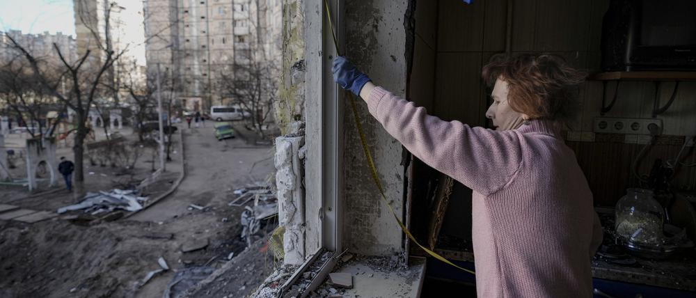 Eine Frau in Kiew misst ein durch Bombenangriffe beschädigtes Fenster aus. Der Vormarsch der russischen Truppen auf die Stadt ist zwar ins Stocken geraten, doch Russland setzt den Beschuss weiter fort.