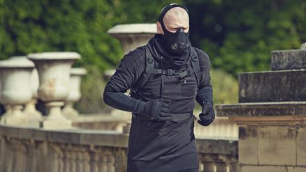 Ein Mann joggt mit Atemschutzmaske in einem Pariser Park.