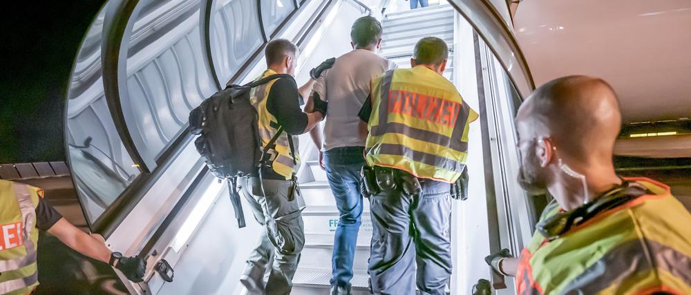 Polizeibeamte begleiten einen Afghanen auf dem Flughafen Leipzig-Halle in ein Charterflugzeug.