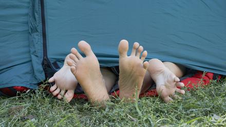 Two people's feet sticking out of tent door.