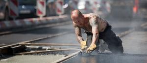 Bei sommerlichen Temperaturen arbeitet Axel mit heißem Teer an Gleisen der Straßenbahnlinie 50 am 26.05.2014 in Berlin-Pankow. Foto: Jörg Carstensen/dpa +++(c) dpa - Bildfunk+++