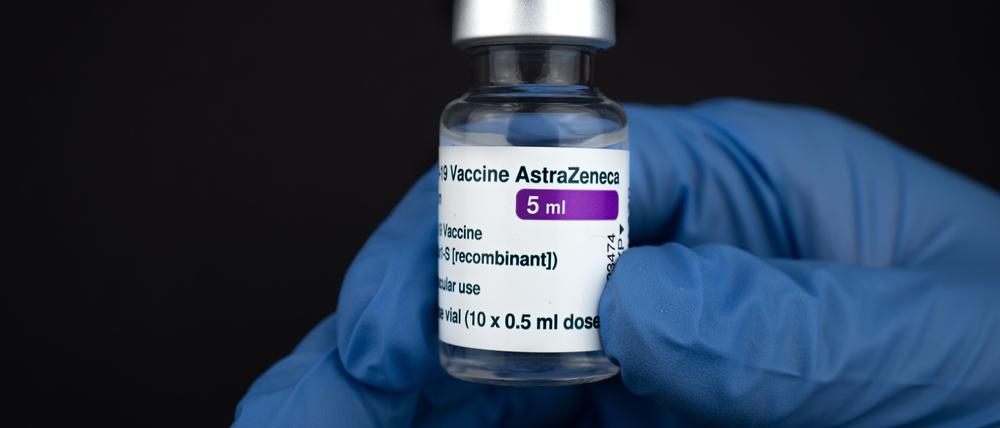 Eine Dosis Astrazeneca in der Hand einer Labormitarbeiter:in mit einem blauen Handschuh.