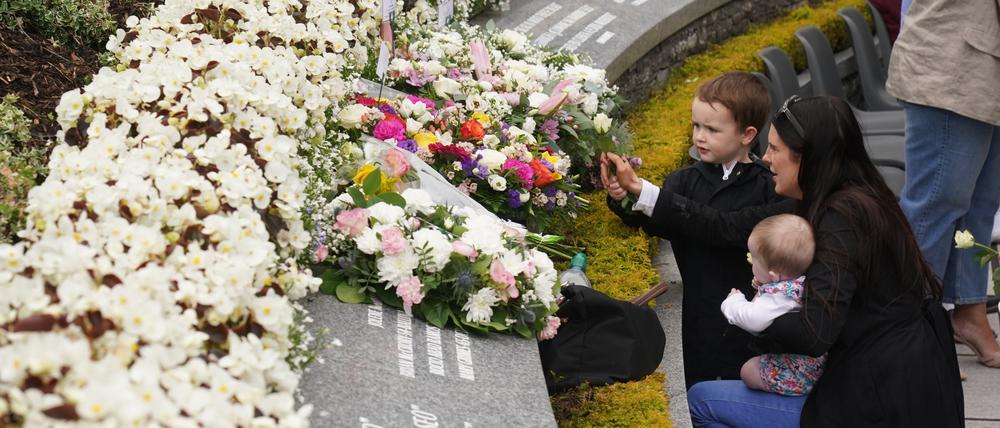 Eine Frau legt im Memorial Garden mit ihren zwei Kindern Blumen nieder während eines Gottesdienstes zum 25. Jahrestag eines Attentats. Die Explosion einer Autobombe in der nordirischen Stadt Omagh am 15. August 1998 jährt sich zum 25. Mal. 